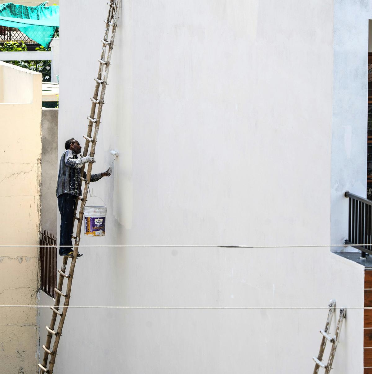 Worker on a ladder against a tall white exterior wall (sample photo)